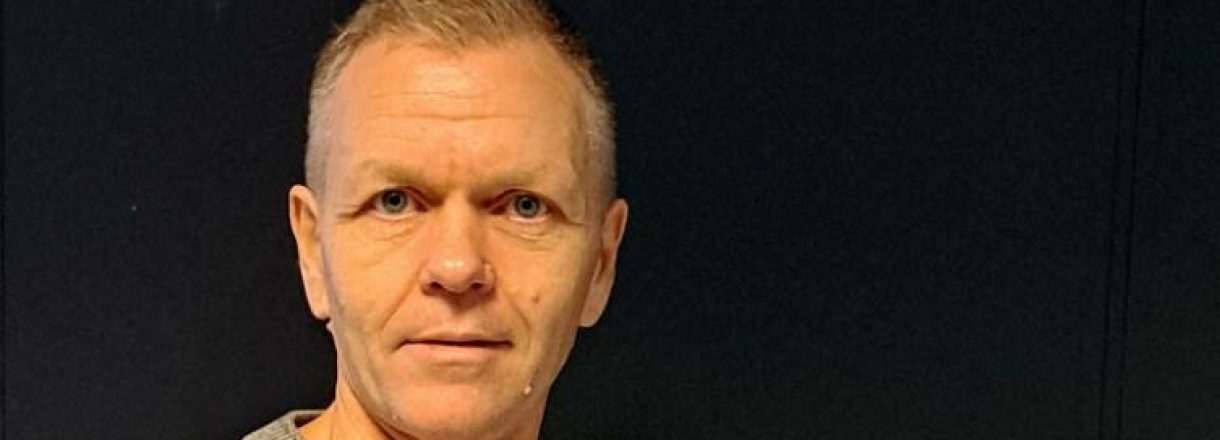 Mann med to bøker om Hamsun framføre mørk vegg
