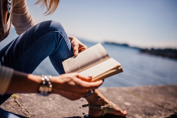 Kvinne som les bok på strand