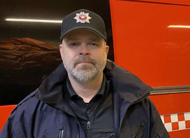Mann i brannuniform foran brannbil